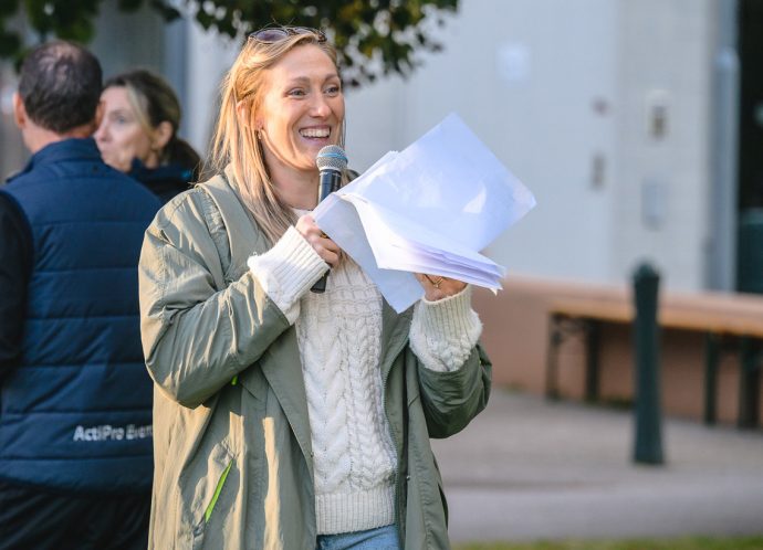 Josefine Goodwin agerar Speaker på Mjärdevistafetten. Hon står och håller i en mikrofon och ser glad ut.